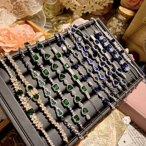 Detail of luxury gold plated bracelets featuring emerald, sapphire, and clear crystals