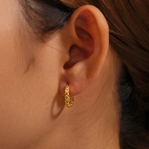 Close-up of a gold S925 sterling silver infinity cross hoop earring on a model ear