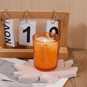 Close-up of a lit orange candle cup on a pink lotus-shaped resin coaster decoration