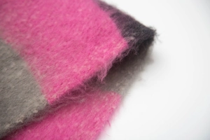 Macro shot of thick striped knit scarf showing pink and purple fuzzy texture details