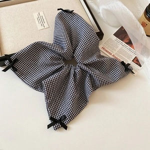 Detailed view of checkered scrunchie with black bows on a vintage aesthetic background