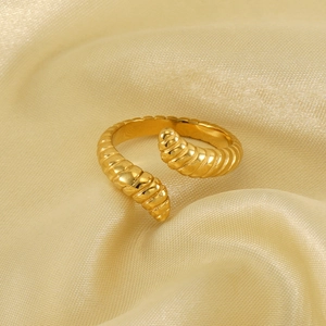 Golden stainless steel caterpillar ring with spiral design on soft silk background