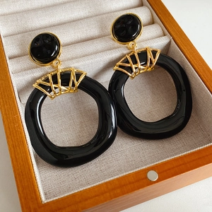Détail de boucles d'oreilles vintage en résine avec éléments géométriques noir et doré