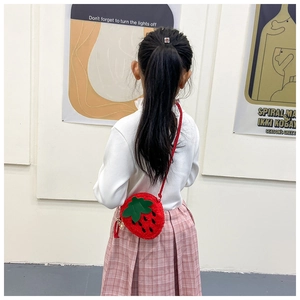 Detail of red plush strawberry crossbody bag for girls with woven strap and leaf accents