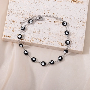 Close-up of silver evil eye bracelet with blue bead details on beige travertine stone