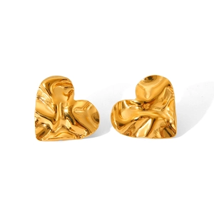 Detail shot of golden heart earrings featuring a modern hammered metal texture finish