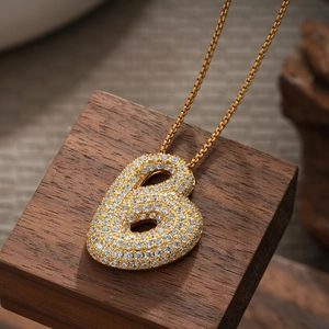 Macro view of 18K gold plated number 6 pendant necklace with sparkling pavé zircons