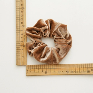 Dettaglio dell'elastico in velluto marrone con trama a coste e diametro di circa 10cm