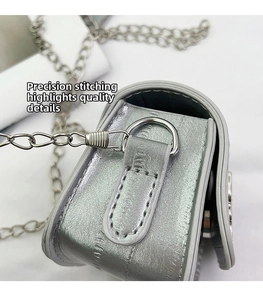 Detailed close-up of precise stitching and silver chain link on a mini saddle bag