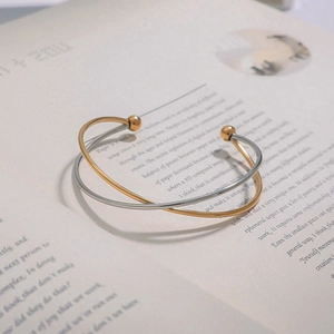 Detail of cross-over bangle with gold and silver finishes on an open book