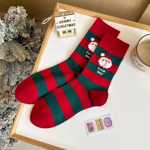Détail de chaussettes de Noël rayées rouge et vert avec broderie Père Noël et texte LUCK DAY