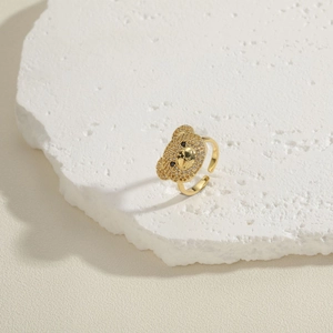 Macro shot of gold-plated open ring with teddy bear head paved in cubic zirconia