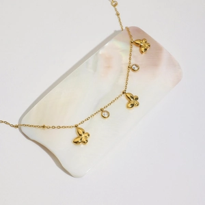 Close-up of gold 18K butterfly bracelet with zircons on a white pearl shell