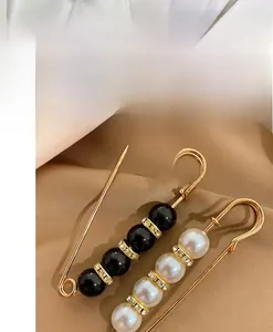 Detailed shot of pearl and crystal gold safety pin brooches on brown satin fabric