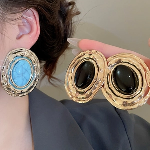 Dettaglio orecchini vintage dorati con pietre ovali turchesi e nere effetto retrò