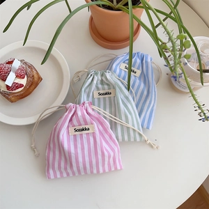 Close-up of three striped cotton drawstring storage bags in pink, green, and blue hues