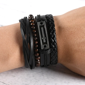 Close-up of multilayered handmade braided leather bracelets with wooden beads and metal cross