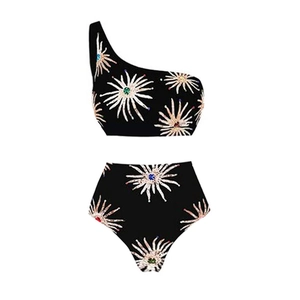 Detail of one-shoulder bikini set featuring black fabric with white starburst patterns