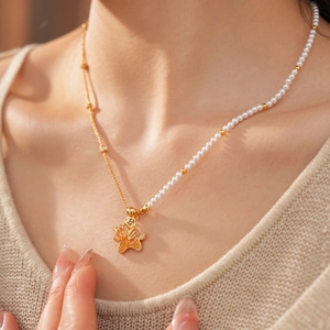 Detail of 18k gold plated beaded pearl necklace with a dragon pendant and zircon
