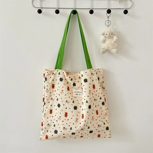 Detail of quilted canvas tote bag featuring bear prints and green shoulder straps