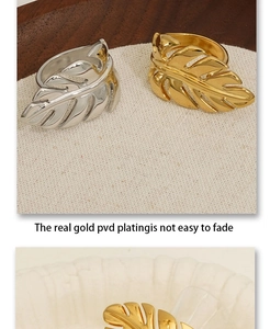 Detailed view of gold and silver leaf shaped rings on a white textured fabric background