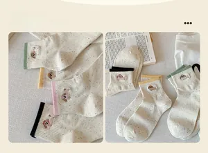 Detailed view of beige confetti knit socks with cute dog embroidery and striped cuffs