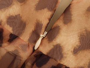 Macro view of leopard print dress fabric showing brown texture and beige zipper detail