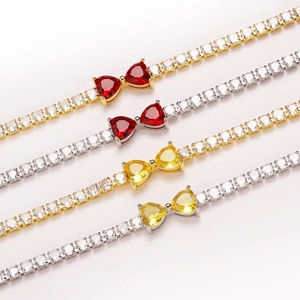 Close-up detail of silver and gold tennis bracelets with red and yellow heart stones