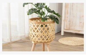 Detail of Nordic bamboo woven planter with wooden tripod legs and monstera plant