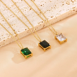 Macro detail of French vintage square glass pendants in green, black and clear on gold chain