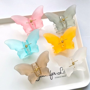 Detailed top view of large matte butterfly hair clips in six pastel colors on a white tray