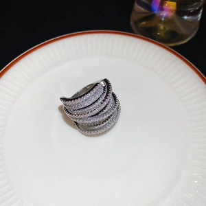 Macro detail of multi-layer wrap ring with pavé-set cubic zirconia on a white plate