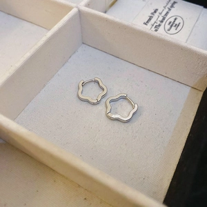 Close-up of small silver hollow flower earrings displayed in a jewelry box