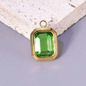 Detailed macro shot of a gold rectangular pendant with an emerald green crystal stone
