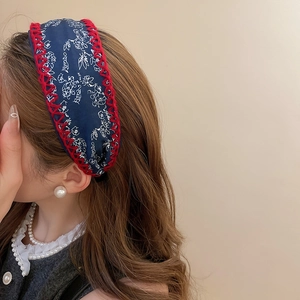 Detail of floral printed knotted headband in navy blue with red stitched edges on model