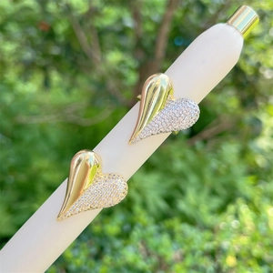 Detail showing gold heart-shaped earrings with half-pave sparkling crystals on a white stand