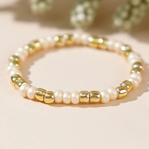 Elegant beaded ring featuring cream faux pearls and gold square beads in a modern design