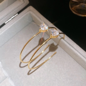 Gros plan détaillé de boucles d'oreilles créoles dorées avec zircons en forme de cœur brillant