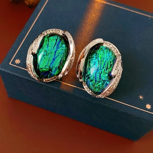 Close-up of vintage oval resin earrings with green and blue stones on jewelry box