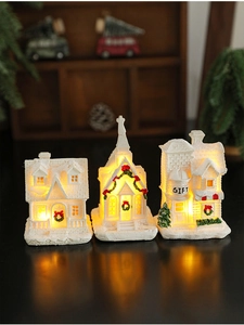 Macro detail of three glowing resin Christmas houses with warm LED lighting on a dark surface