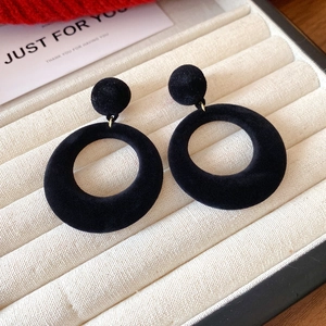 Close-up of elegant black velvet hoop earrings displayed on a cream jewelry tray