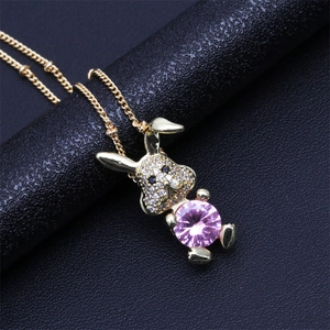 Macro shot of gold rabbit pendant with micro-pave crystals and pink faceted gemstone