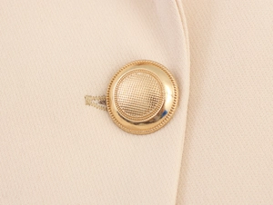 Macro view of gold vintage button and textured beige fabric on elegant suit jacket