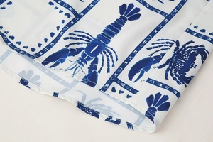 Detail of blue lobster and crab print on white woven fabric with clean hem stitching