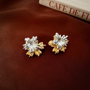 Detailed close-up of bicolored floral stud earrings with textured brushed metal finish
