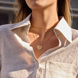Close-up of double-layered gold heart necklace with sparkling crystals on a model