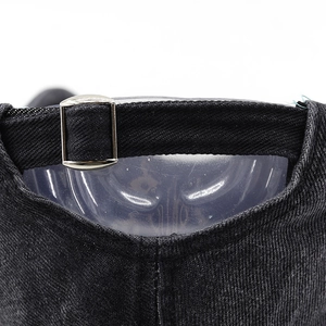 Macro detail of adjustable silver metal buckle on washed denim distressed baseball cap