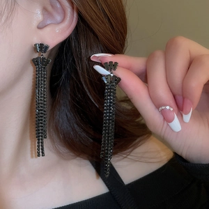 Close-up of long black fringe earrings with rhinestones worn by a model in lifestyle shot