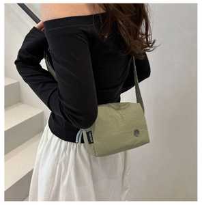 Borsa a tracolla in nylon verde oliva che mostra dimensioni e vestibilità su una modella