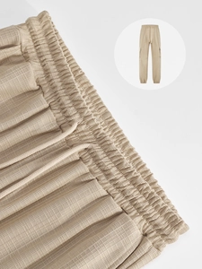 Close-up of elastic waistband with adjustable drawstring on waffle texture beige cargo pants